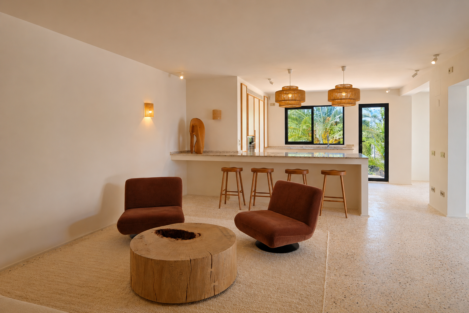 Open woonruimte met twee roestkleurige fauteuils, een rustieke houten salontafel en een lichte terrazzovloer. De bar is voorzien van geweven hanglampen en biedt uitzicht op weelderig groen.