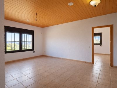 Ruime kamer met lichte tegelvloer, witte muren en een warm houten plafond. De ramen met tralies bieden een weids uitzicht op de vallei en veel natuurlijk licht.