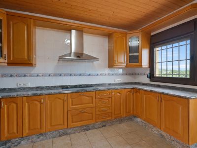 Uitgeruste keuken met houten kasten, granieten werkbladen en een houten lamellenplafond. Raam met tralies biedt uitzicht naar buiten.