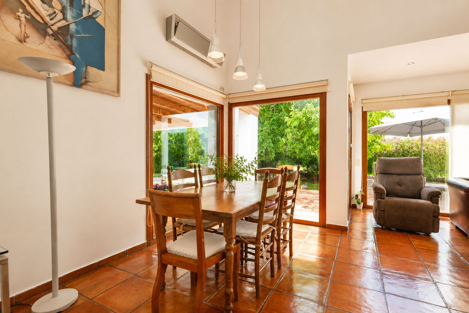 Lichte hoofdwoning woonkamer met handgemaakte terracotta vloeren, een dubbelzijdige open haard en grote ramen, die de ruimte vullen met natuurlijk licht en mediterrane sfeer.