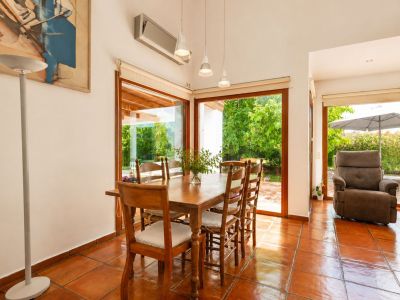 Lichte hoofdwoning woonkamer met handgemaakte terracotta vloeren, een dubbelzijdige open haard en grote ramen, die de ruimte vullen met natuurlijk licht en mediterrane sfeer.