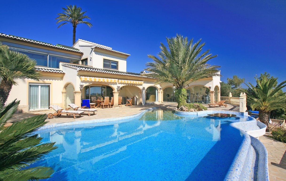 Ruim blauw mozaïekzwembad met strandachtige toegang, palmeiland en watertafel. De villa heeft een overdekte naya en een glazen fitnessruimte.