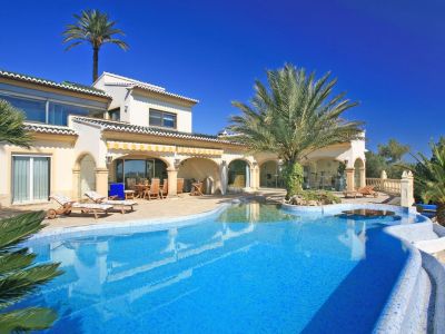 Ruim blauw mozaïekzwembad met strandachtige toegang, palmeiland en watertafel. De villa heeft een overdekte naya en een glazen fitnessruimte.