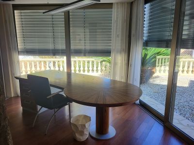 Ruime privékantoor met een groot houten bureau en parketvloer. De kamerhoge ramen bieden uitzicht op een balustrade en mediterrane tuin.