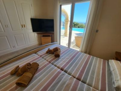 Slaapkamer met twee eenpersoonsbedden, ingebouwde kledingkast en een wand-tv. Directe toegang tot het buitenzwembad met boog en vrij uitzicht.
