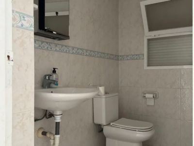 Functionele badkamer met lichte tegels, decoratieve rand en een kiepraam. Voorzien van een hangende wastafel, toilet en spiegelkast met geïntegreerde verlichting.