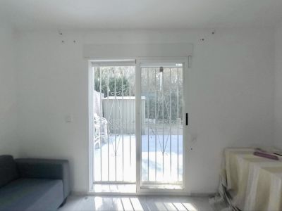 Ruime kamer met glazen schuifdeuren en veiligheidshekken, direct toegang tot de privétuin, verlicht door overvloedig natuurlijk licht op de lichte vloer.