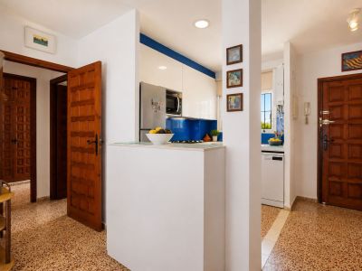 De entreehal toont opvallende vloertegels met patroon en klassieke houten deuren. Een moderne keuken met blauwe achterwand en witte kasten is zichtbaar, gescheiden door een functionele bar.