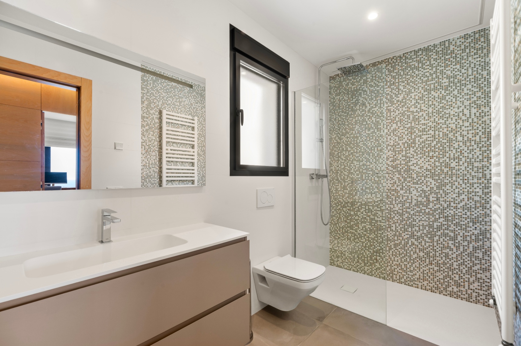 Moderne badkamer met inloopdouche en mozaïekwand in aardetinten. Voorzien van een zwevend wastafelmeubel met geïntegreerde wasbak, een wandcloset en een zwart kozijnraam. Moderne badkamer met inloopdouche en mozaïekwand in aardetinten. Voorzien van een zwevend wastafelmeubel met geïntegreerde wasbak, een wandcloset en een zwart kozijnraam.