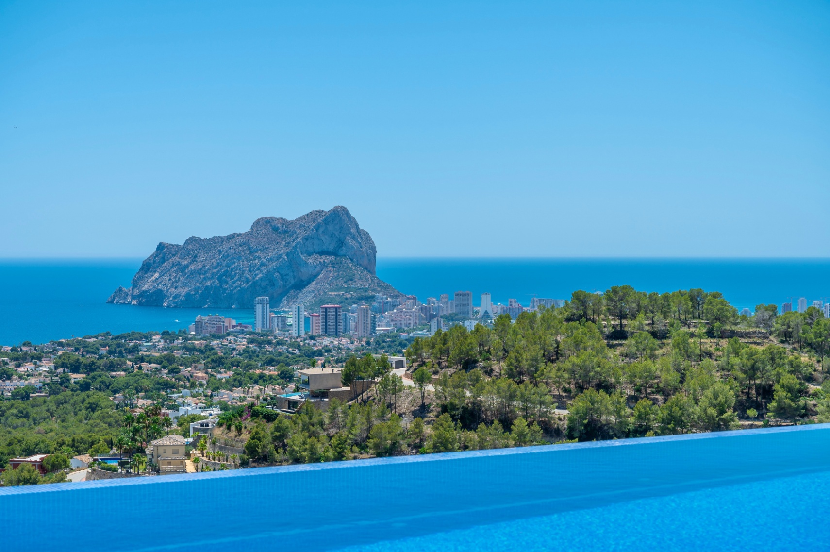 Rand van overloopzwembad met panoramisch uitzicht op de Middellandse Zee, Calpe en de iconische Peñon de Ifach. Rand van overloopzwembad met panoramisch uitzicht op de Middellandse Zee, Calpe en de iconische Peñon de Ifach.