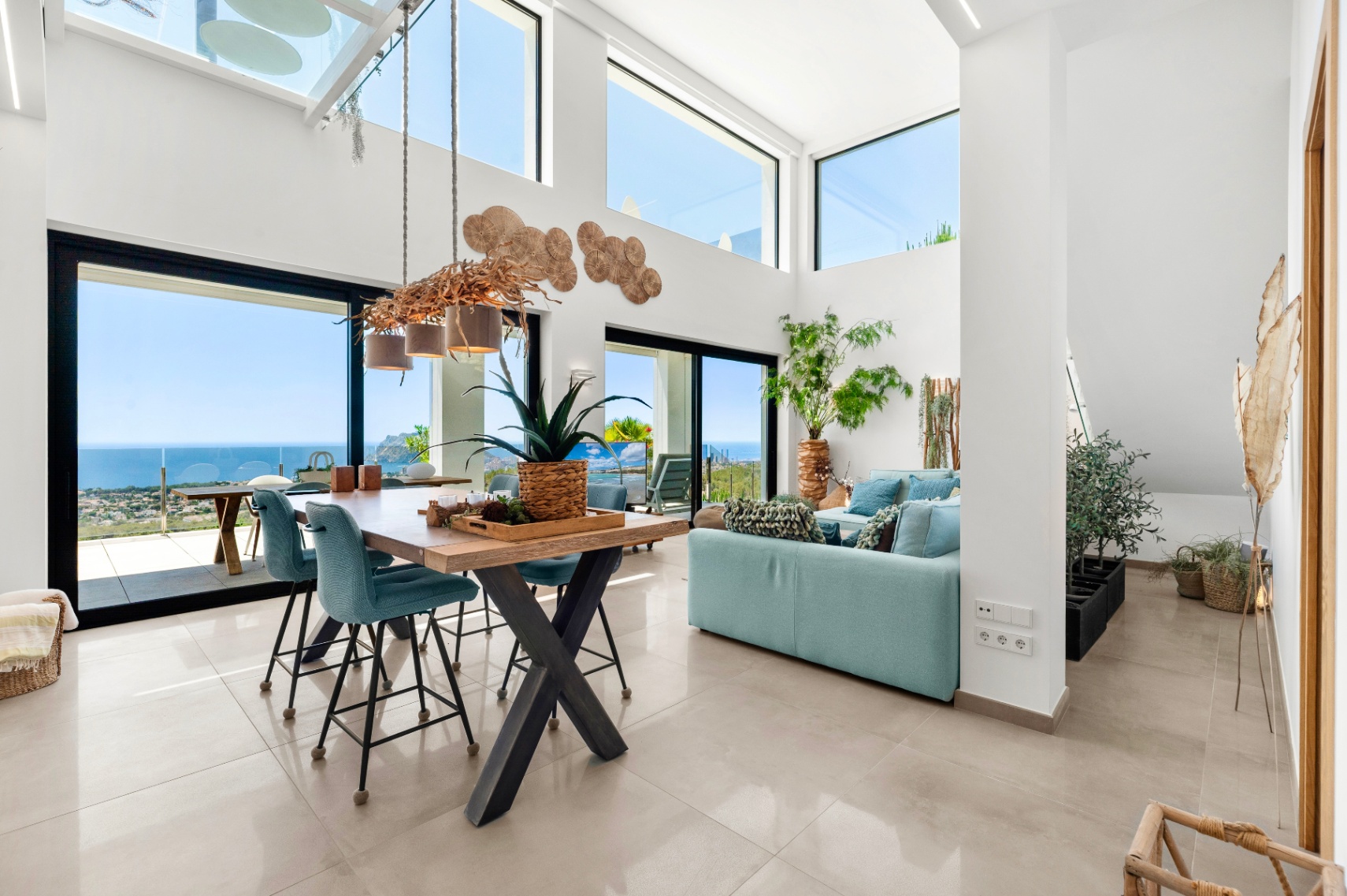 Ruime open woon- en eetkamer met hoge plafonds, grote ramen en een unieke takkenkroonluchter. Panoramisch uitzicht op zee, de kustlijn en de Peñón de Ifach kenmerken deze lichte ruimte. Ruime open woon- en eetkamer met hoge plafonds, grote ramen en een unieke takkenkroonluchter. Panoramisch uitzicht op zee, de kustlijn en de Peñón de Ifach kenmerken deze lichte ruimte.