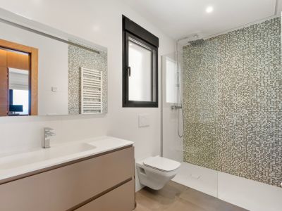 Moderne badkamer met inloopdouche en mozaïekwand in aardetinten. Voorzien van een zwevend wastafelmeubel met geïntegreerde wasbak, een wandcloset en een zwart kozijnraam.