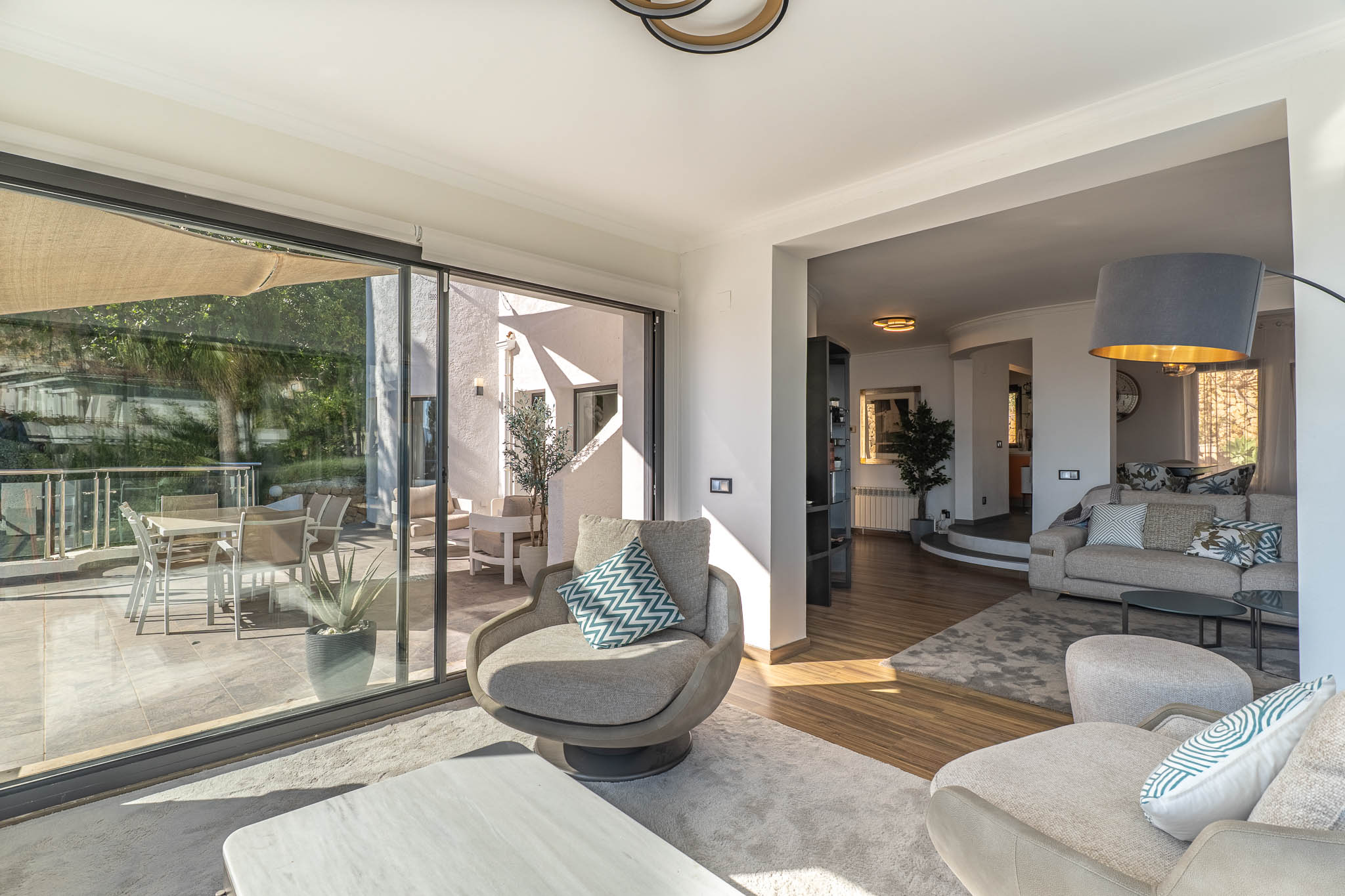 Moderne woonkamer met royale glazen deuren die naadloos op het terras aansluiten, een adembenemend panoramisch uitzicht op de Middellandse Zee en veel daglicht bieden.