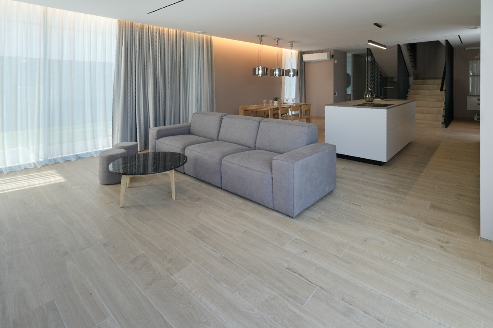 Open woonkamer met grijze modulaire bank, zwarte marmeren salontafel en houtlook tegelvloer. Grote ramen met transparante en grijze gordijnen.