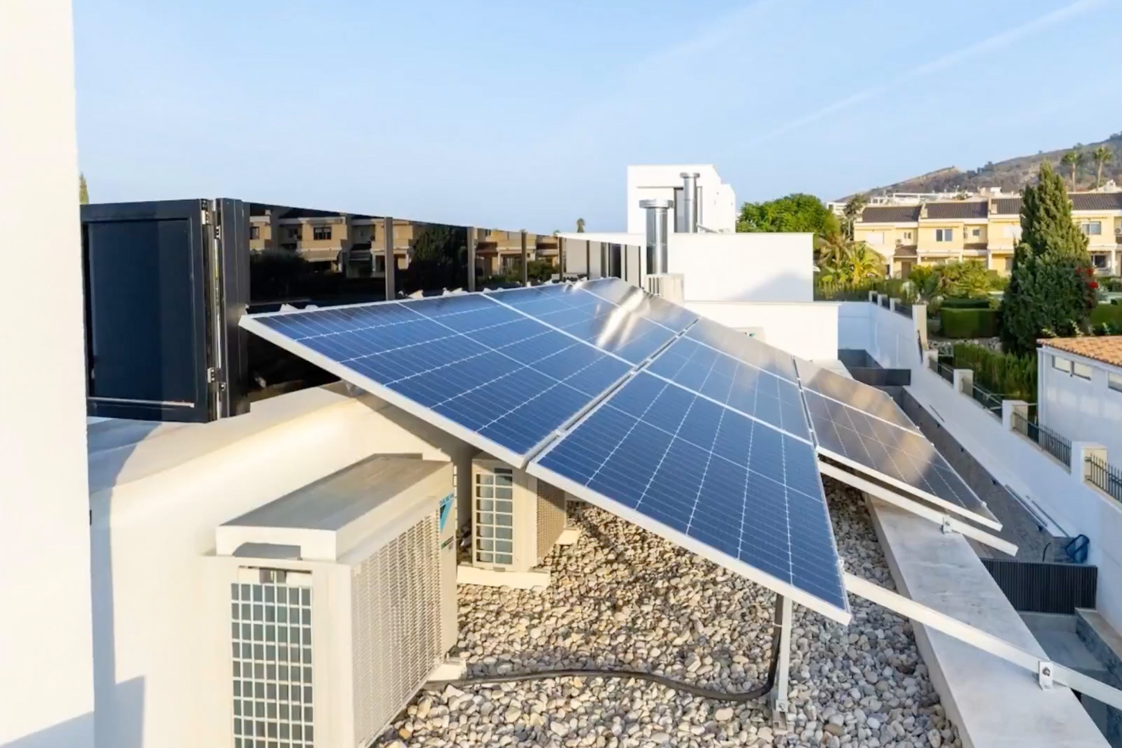 Uitgebreid fotovoltaïsch zonnepanelensysteem op het dak. Klimaatregelingsunits en een licht grindoppervlak completeren deze hoogefficiënte installatie.