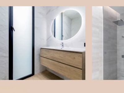 Moderne badkamer met zwevend houten wastafelmeubel, verlichte ovale spiegel en regendouche. Marmerlook en gestructureerde wandtegels.
