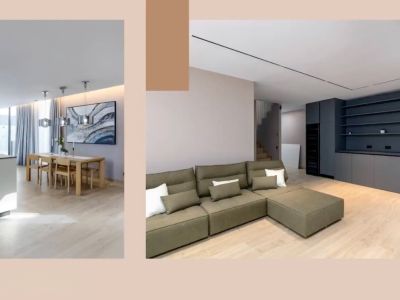 Open leefruimte met modern kookeiland, houten eethoek en olijfgroene hoekbank. Donkergrijze inbouwkasten en strakke verlichting complementeren het design.