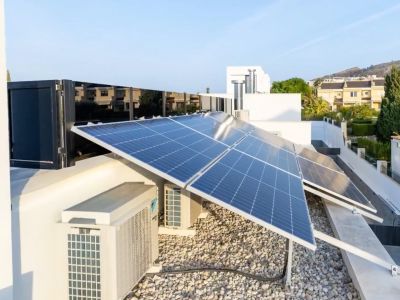 Uitgebreid fotovoltaïsch zonnepanelensysteem op het dak. Klimaatregelingsunits en een licht grindoppervlak completeren deze hoogefficiënte installatie.
