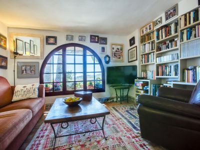 Woonkamer met boogvenster en uitzicht, gedecoreerd met een vloerkleed met motief en een boekenkast vol boeken.
