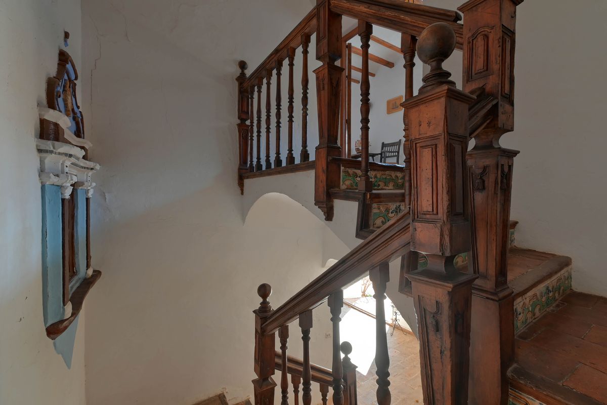 Historische houten trap met gesneden balustrades, terracotta treden en traditionele decoratieve keramische tegels op de stootborden.