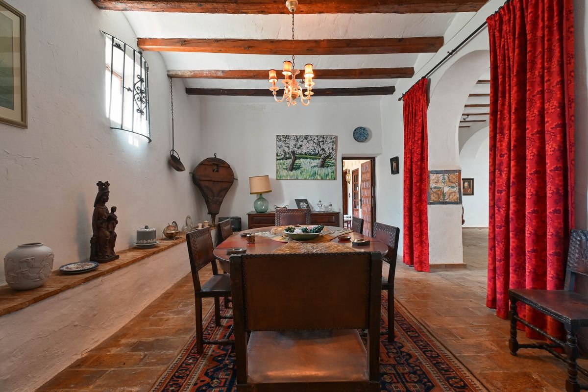 Rustieke eetkamer met authentieke houten plafondbalken, een terracotta tegelvloer en traditionele lederen stoelen bij een karakteristieke toog.