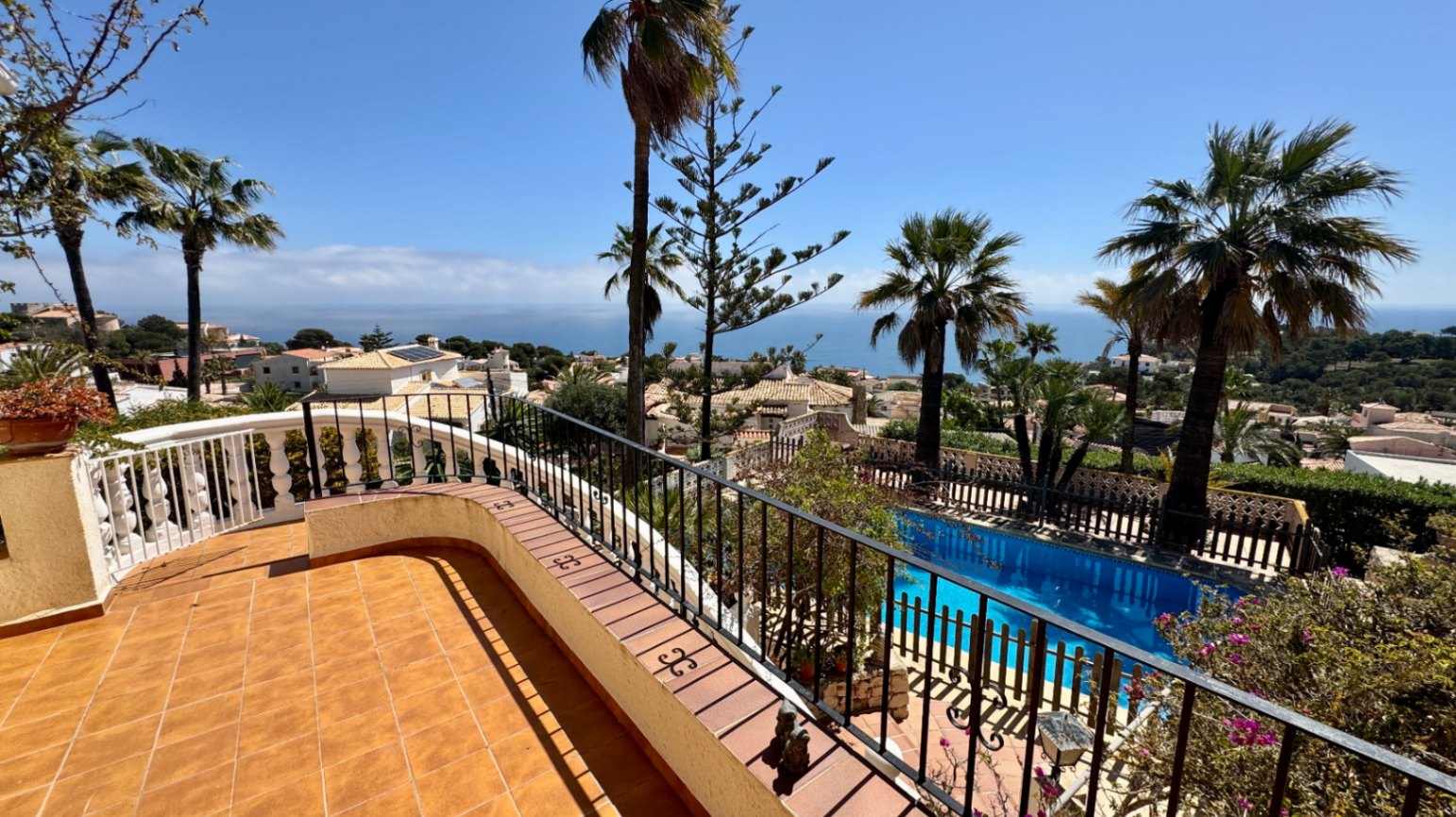 Verhoogd terras met terracotta tegels en smeedijzeren balustrade, uitkijkend over een privézwembad en de Middellandse Zee.