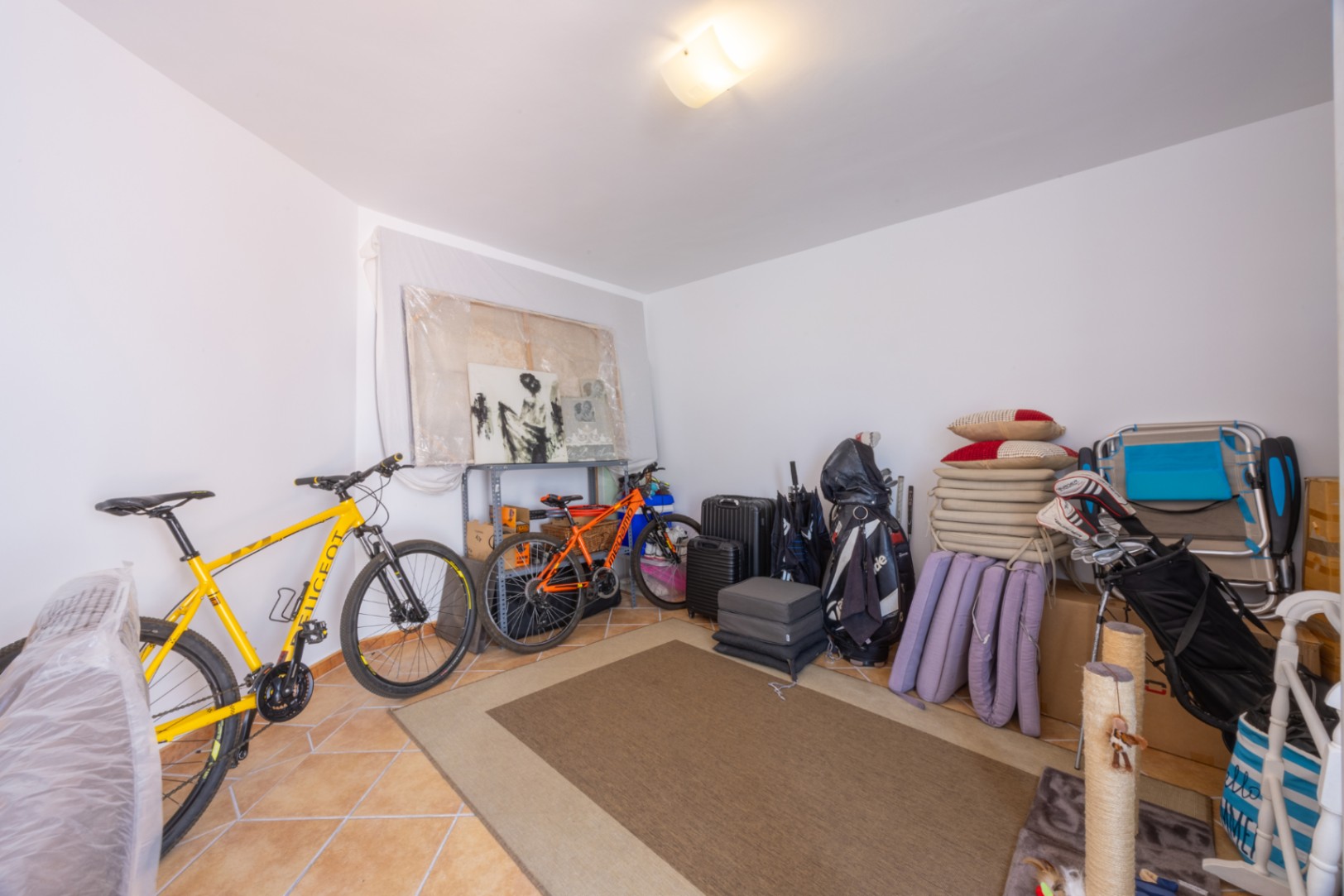 Functionele bergruimte met tegelvloer, geschikt voor het stallen van fietsen, sportuitrusting en diverse persoonlijke eigendommen.