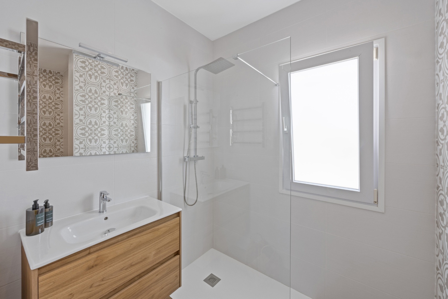 Moderne badkamer voorzien van een houten wastafelmeubel, inloopdouche met glazen wand en witte wandtegels met een subtiel patroonaccent.