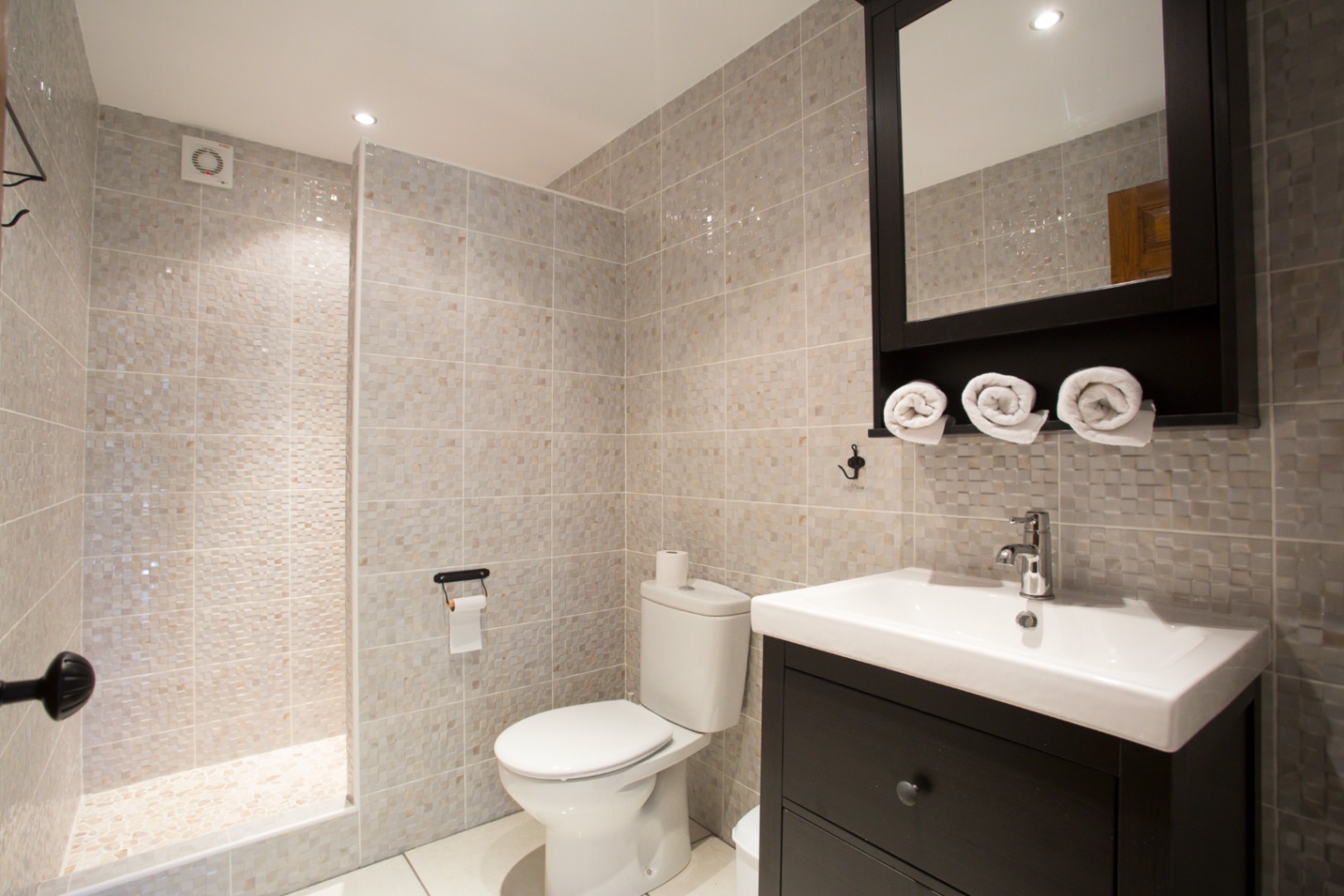 Moderne badkamer met inloopdouche voorzien van mozaïektegels, een donkerhouten wastafelmeubel en een bijpassende spiegelkast.
