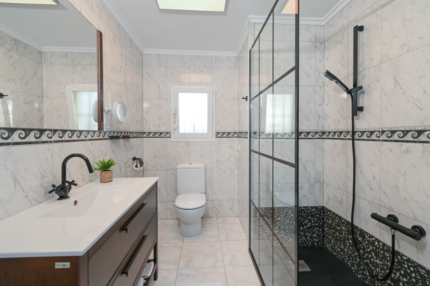 Moderne badkamer met marmerlook tegels, donkerhouten wastafelmeubel en een inloopdouche met een zwart metalen frame en zwarte kranen.