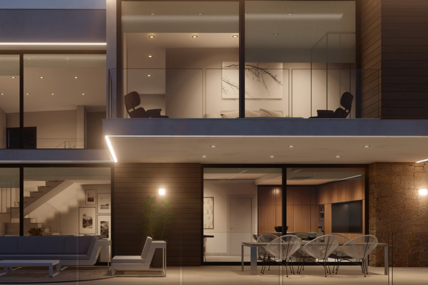 Nachtzicht van een villa met terras, Acapulco-stoelen en natuurstenen muren. Grote glaspartijen verlichten de keuken en het bovenbalkon met glazen balustrade.