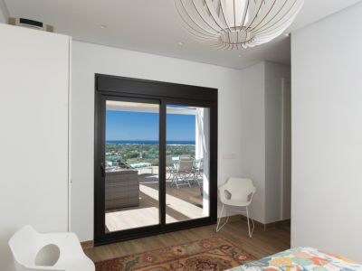 Lichte slaapkamer met directe toegang tot een privéterras en panoramisch uitzicht. Opvallende bolvormige hanglamp en moderne stoelen sieren de ruimte.