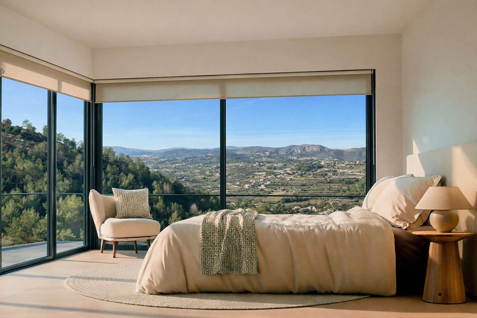 Slaapkamer met kamerhoge hoekramen en panoramisch uitzicht op de vallei en bergen. Voorzien van neutrale tinten, een houten bijzettafel en natuurlijk licht.