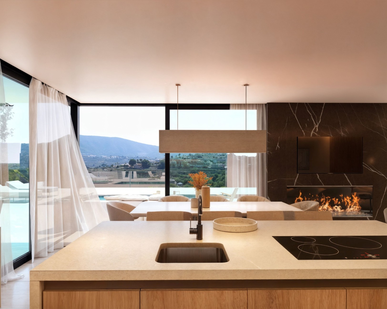 Open keuken met stenen kookeiland, aansluitend eetgedeelte en woonkamer met een donker marmeren haardwand en panoramisch uitzicht over de vallei.