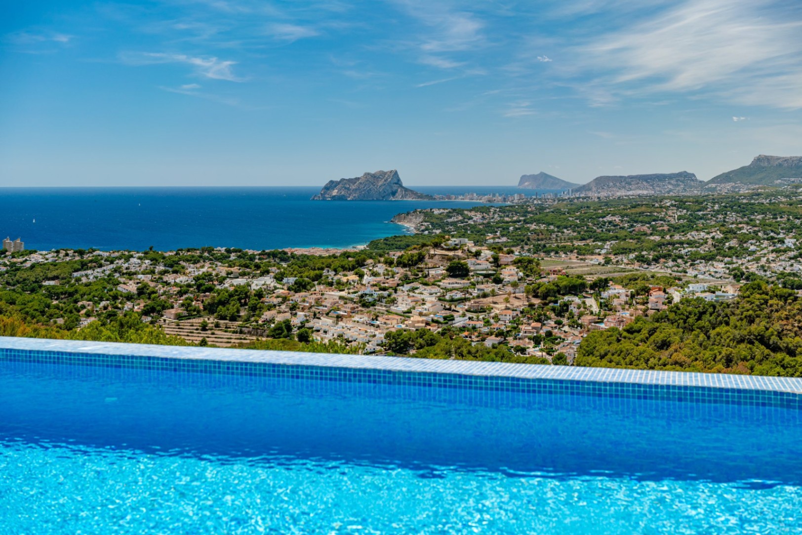 Infinity zwembad met blauwe mozaïektegels en panoramisch uitzicht op de Middellandse Zee, de Peñón de Ifach en de kustlijn van Calpe.