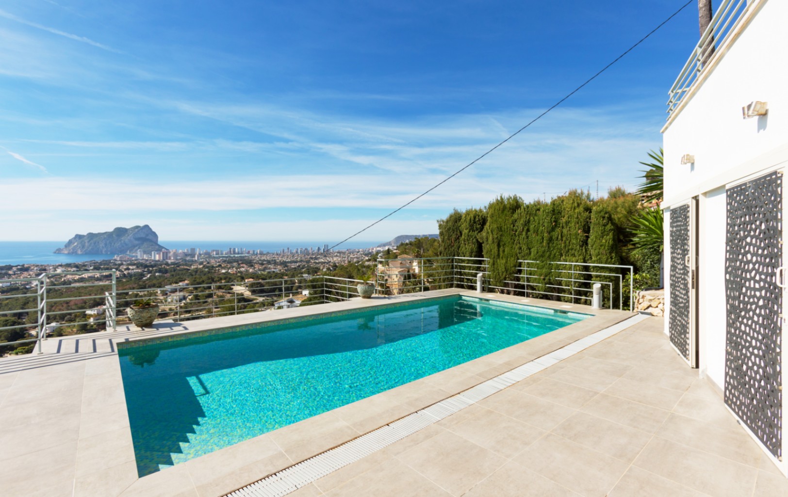 Rechthoekig buitenzwembad met betegeld terras en metalen reling, met panoramisch uitzicht op de Middellandse Zee en de Peñón de Ifach in Calpe.