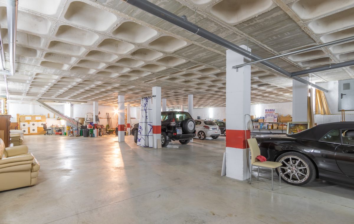 Ruime ondergrondse garage met een cassetteplafond van beton, structurele kolommen met rode markeringen en veel plek voor meerdere auto's en opslag.