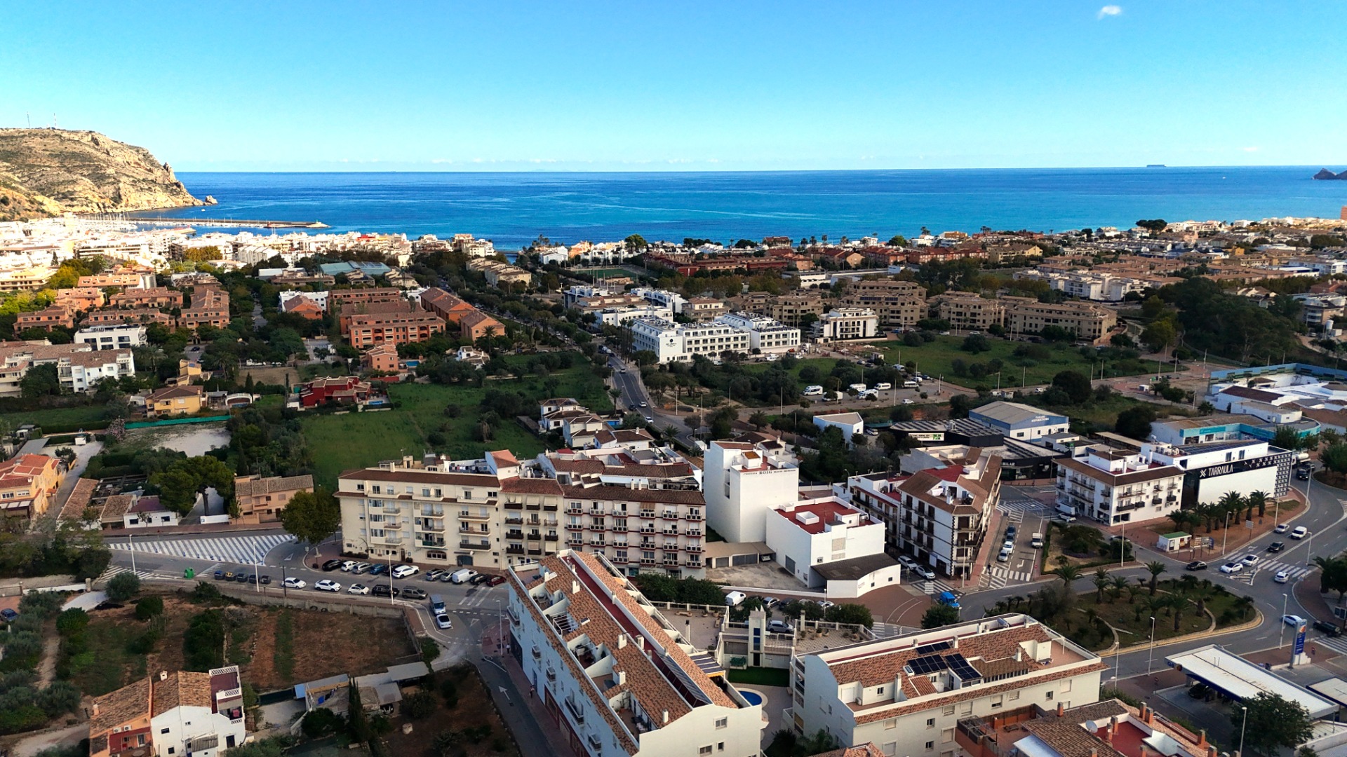 Verhoogd panoramisch uitzicht op het stadslandschap van Jávea, met mediterrane architectuur, het havengebied en de blauwe zee onder een heldere hemel.