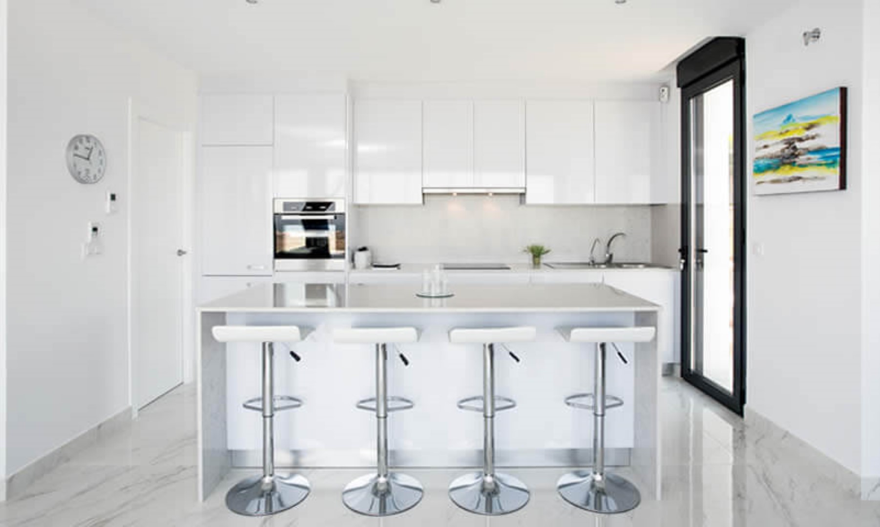 Moderne open keuken met witte hoogglanskasten, een kookeiland met kwarts werkblad en vier barkrukken. Porseleinen vloertegels met een verfijnde marmerlook.