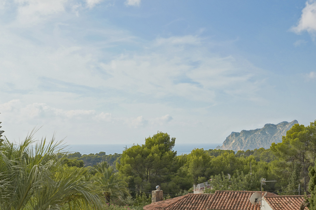 Panoramisch uitzicht op de Middellandse Zee en de Peñón de Ifach vanaf de bovenverdieping, omgeven door weelderige pijnbomen en lokale vegetatie.