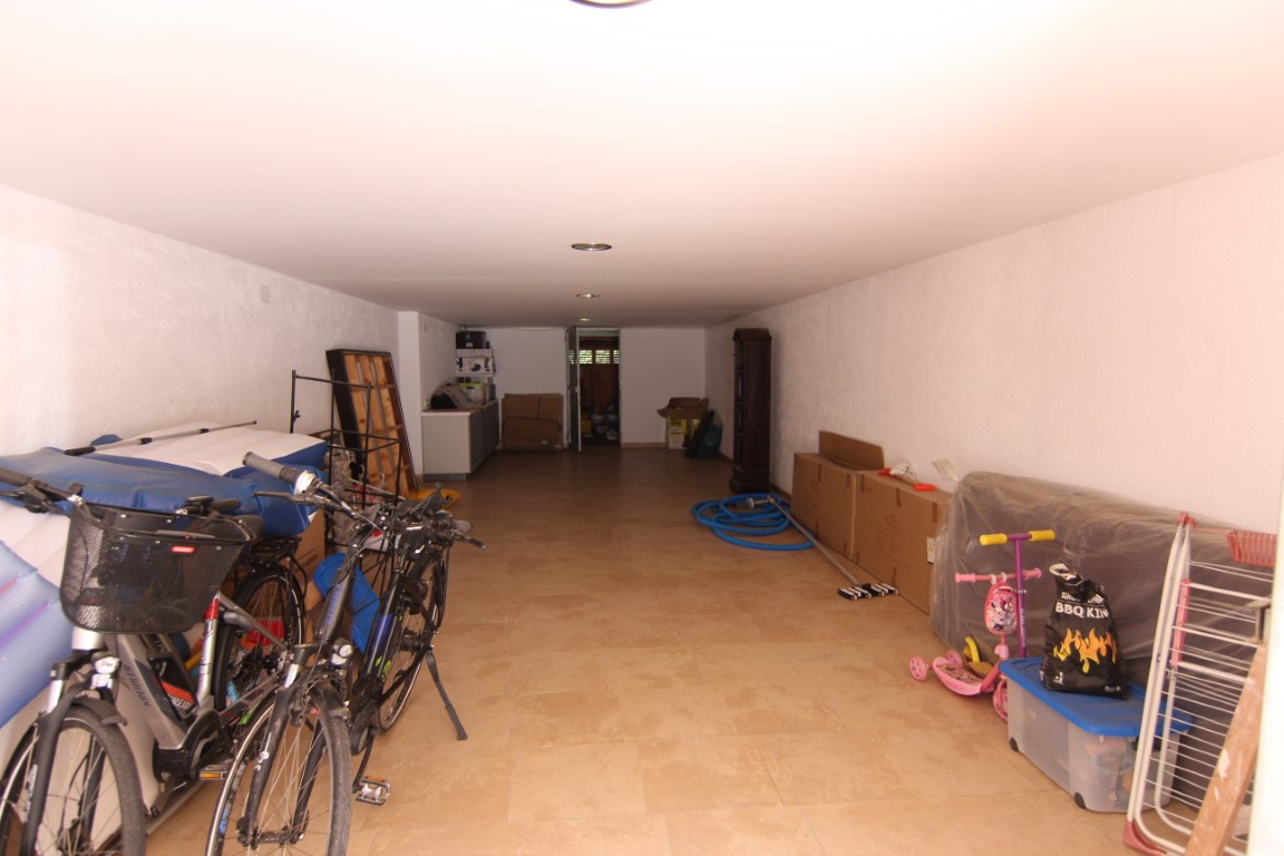 Ruime garage van 60m2 met tegelvloer, witte wanden en inbouwspots, wat zorgt voor aanzienlijke opslagruimte en parkeergelegenheid.