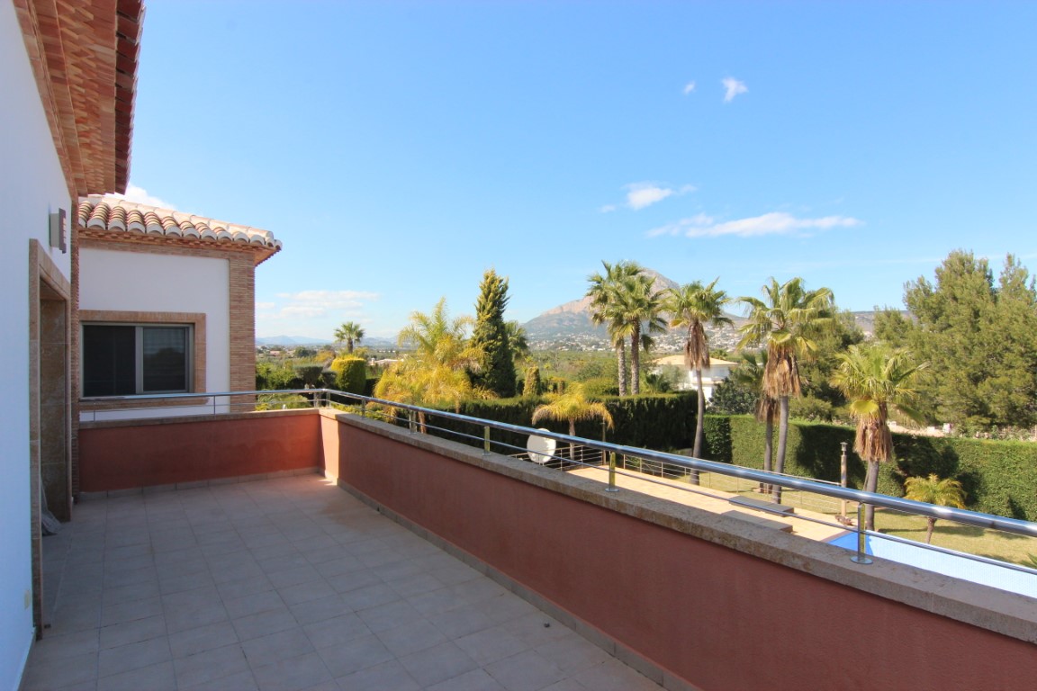 Terras op de eerste verdieping met rvs-balustrade en uitzicht op de mediterrane tuin, het zwembad en de omliggende bergen van Jávea.