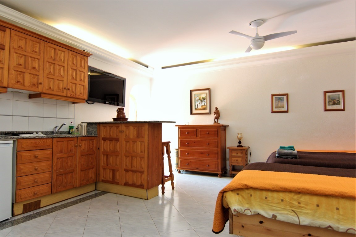 Studio-appartement met houten kitchenette, granieten werkblad en twee eenpersoonsbedden. Voorzien van een plafondventilator, tegelvloer en sfeervolle indirecte verlichting.