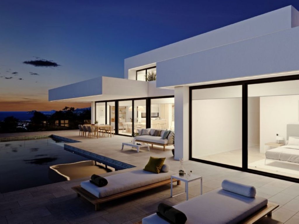 Moderne villa bij zonsondergang met kamerhoge glazen puien, een ruim terras van natuursteen, infinity pool en panoramisch zeezicht.