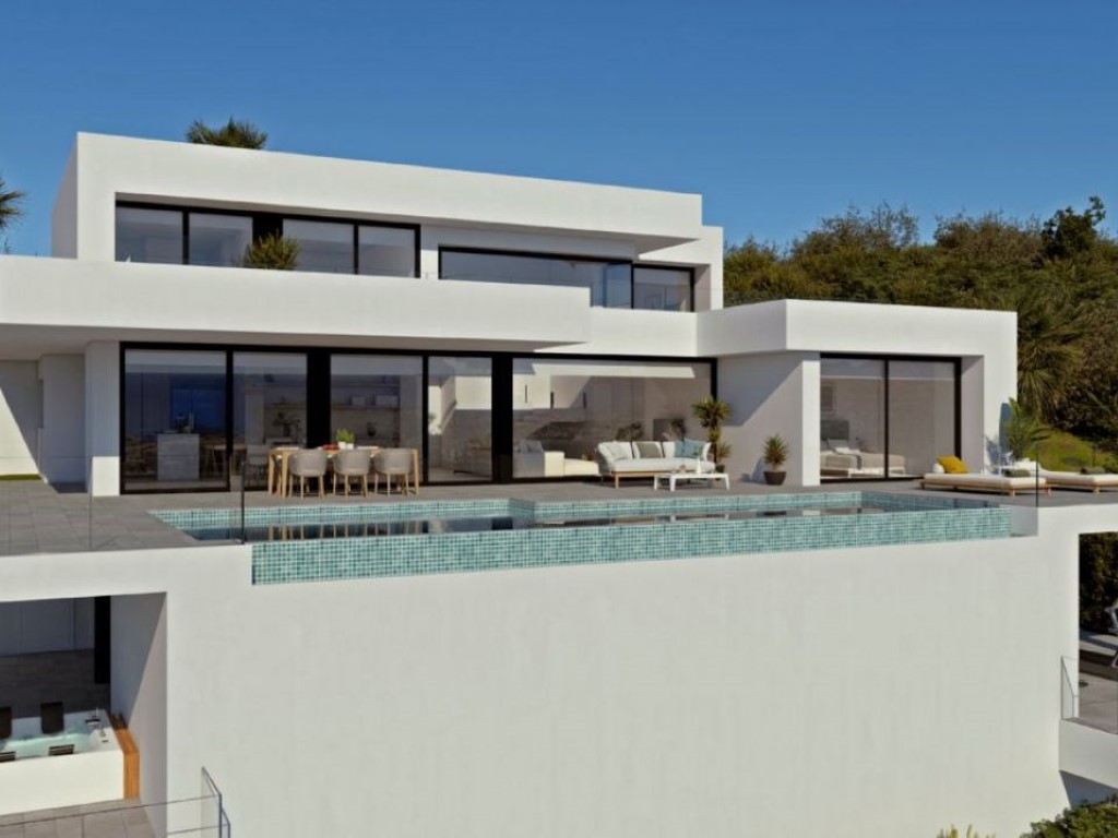 Moderne witte villa met overloopzwembad van turquoise mozaïek, ruime terrassen en kamerhoge glazen schuifdeuren die binnen en buiten naadloos verbinden.