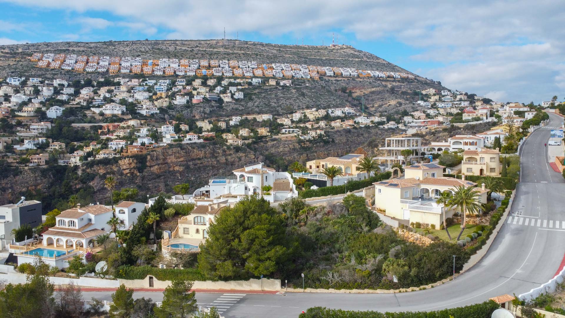 Panoramisch luchtfoto van de woonwijk Cumbre del Sol, met de indeling van de villa's op de heuvel en het mediterrane landschap.