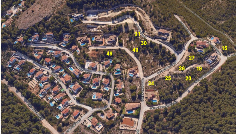 Luchtfoto van de verkaveling in Jávea, met de indeling van genummerde bouwpercelen te midden van beboste heuvels en een volledige infrastructuur.