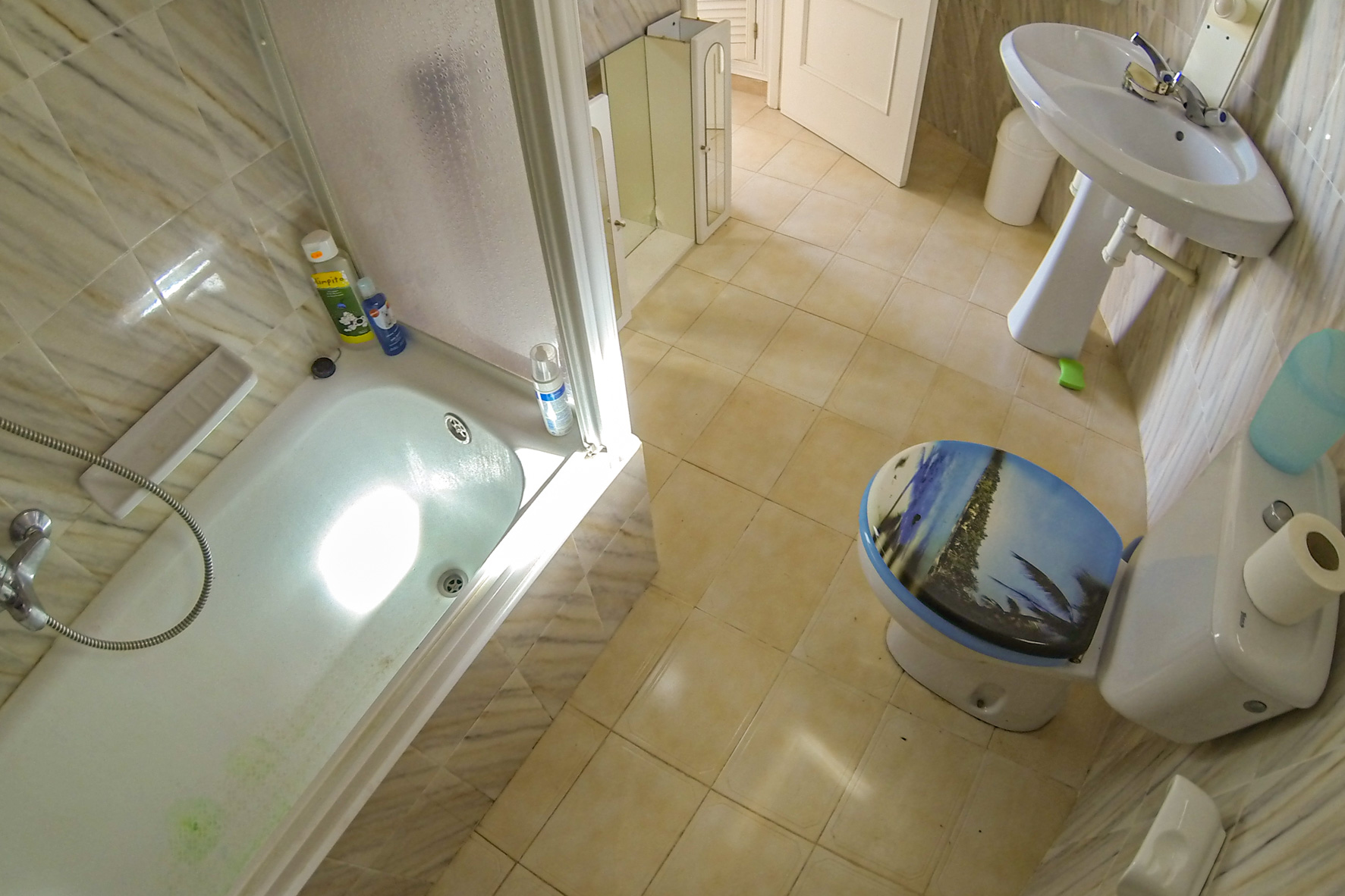 Badkamer met ligbad, wastafel en toilet met een versierd deksel.