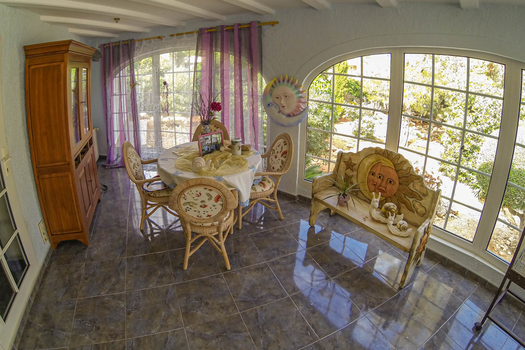Lichte eethoek met ronde tafel, rieten stoelen en decor met thema zon en maan.
