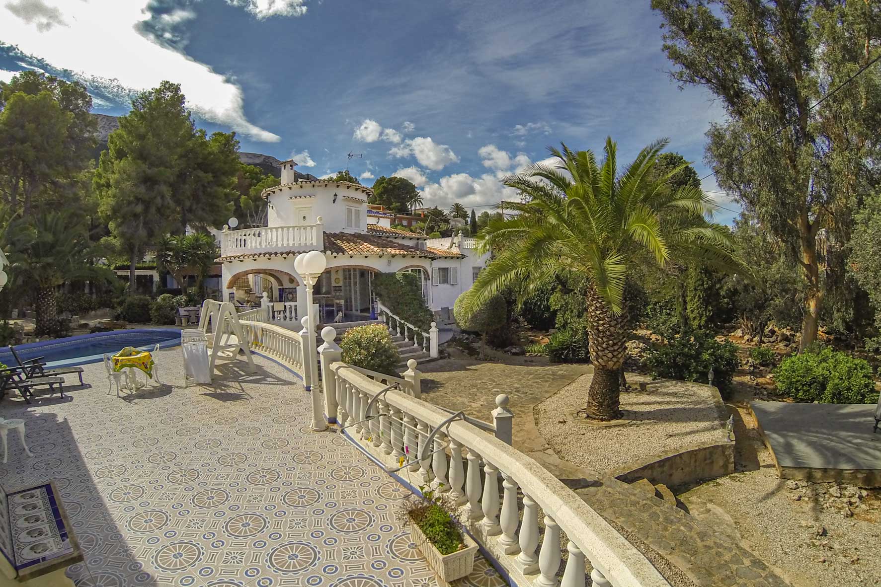 Uitzicht op het terras met tegelpatroon, de balustrade en het zwembad van de villa.